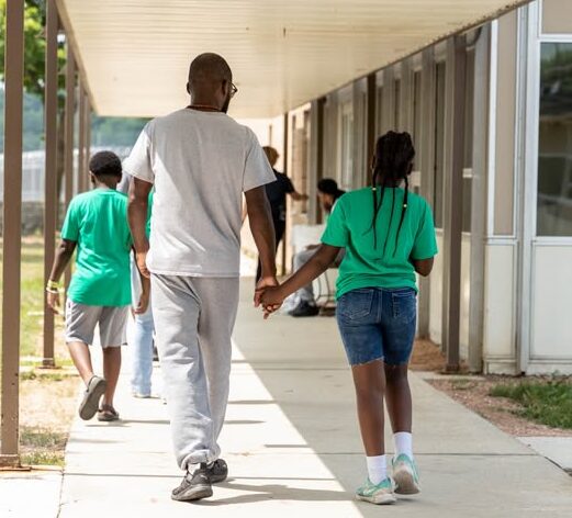 Father and daughter holding hands walking.
